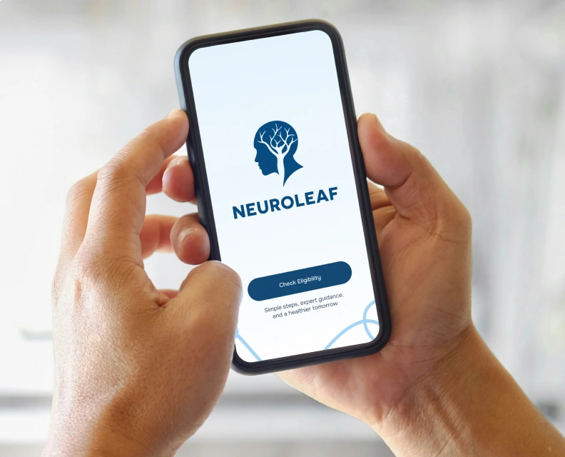 Person holding a smartphone displaying the Neuroleaf app on the screen. The app's logo features a silhouette with a tree brain design above the text.